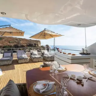 The spacious unobstructed sundeck has a jacuzzi pool with a large sunbathing area all around it, a bar, a dining table and sunbeds