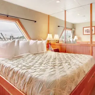 'Commodore Suite' - A1-A2. Bridge Deck. Separate sitting area; king or twin beds; view window and a sliding glass door opening to a small balcony; private bath with Jacuzzi tub and shower. Triple accommodation available.